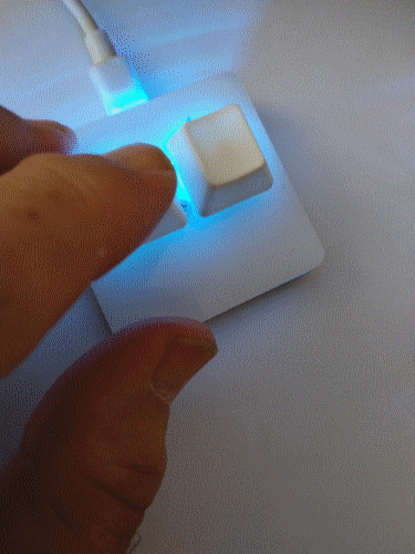 Un doigt appuie sur un petit contrôleur à touches, éclairé en bleu